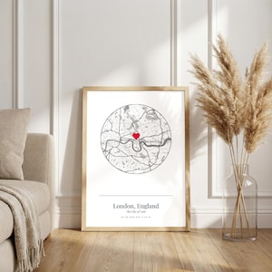 Könnte beinhalten: Ein gerahmter Druck mit einer kreisförmigen Karte von London, England, mit einem roten Herz, das einen Ort markiert. Der Druck enthält den Text "London, England" und "The City of Love". Der Rahmen ist goldfarben.
