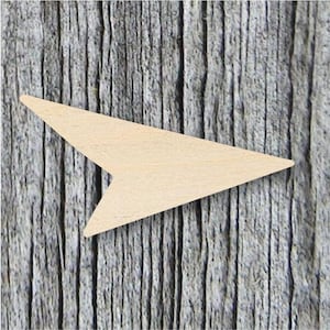 May include: A wooden arrow shape, cut from a light brown piece of wood. The arrow is pointing to the right.