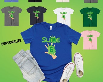 May include: A blue toddler t-shirt with a green slime hand print and the text "Slime 6". The shirt is available in a variety of colors.