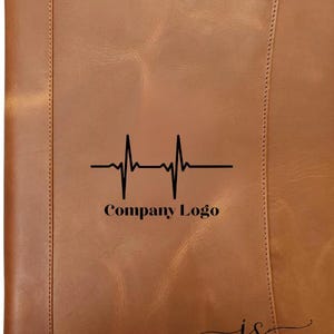 May include: A brown leather portfolio with a black heartbeat graphic and the text "Company Logo". The portfolio has a stitched border and the initials "js" in the bottom right corner.