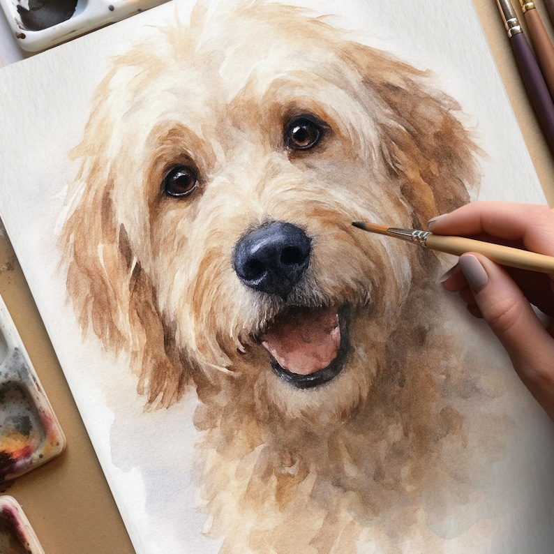 May include: Watercolor painting of a golden doodle dog with a happy expression. The dog has brown eyes, a black nose, and a light brown coat. A hand holding a paintbrush is visible, suggesting the artwork is in progress.