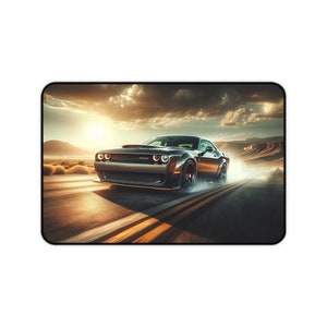 May include: Mousepad featuring a black muscle car speeding down a desert highway at sunset. The car is dark gray with orange accents, leaving a trail of smoke. The background includes a dramatic sky and desert landscape.