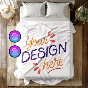 May include: White fleece blanket with the text "Your Design Here" in orange, purple, and red lettering. The blanket is folded and lying on a bed with white pillowcases.
