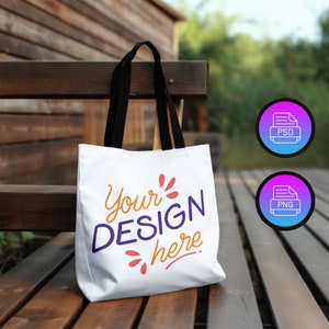 Könnte beinhalten: Weiße Einkaufstasche mit schwarzen Henkeln, die auf einer Holzbank steht. Die Tasche hat den Text "Your Design here" in Lila und Orange aufgedruckt.