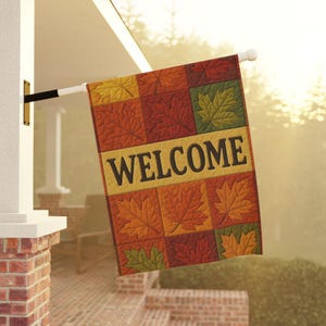 Puede incluir: Una bandera de bienvenida rectangular con temática otoñal. La bandera presenta un diseño de retazos de hojas de arce en tonos de rojo, naranja, amarillo y verde. La palabra "WELCOME" se muestra en letras grandes y negras.