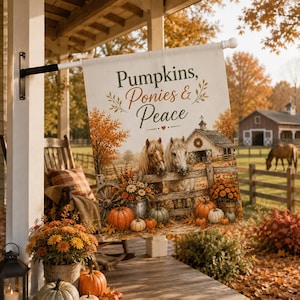 May include: A rectangular garden flag featuring the text Pumpkins, Ponies & Peace. The design displays two horses behind a wooden fence, a barn, orange pumpkins, and autumn foliage. The flag is mounted on a black metal pole on a porch.