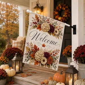 May include: A rectangular garden flag featuring the word Welcome in black cursive script, surrounded by a decorative border of autumn-themed flowers and foliage in shades of orange, red, yellow, and cream, mounted on a white metal pole.