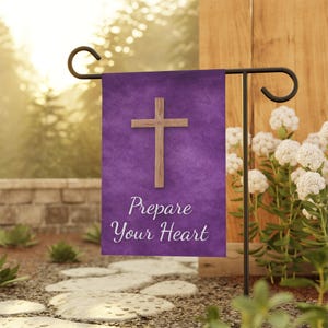May include: A purple garden flag featuring a wooden cross and the words "Prepare Your Heart" in white script. The flag is mounted on a black metal stand, set in a garden with white flowers and a stone pathway.