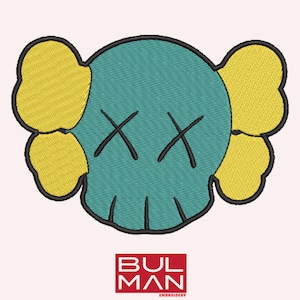 Puede incluir: Diseño bordado con una forma de calavera turquesa con ojos de 'X' negros y formas amarillas en forma de oreja a cada lado. El diseño está delineado en negro. El texto "BULMAN EMBROIDERY" está en un cuadro rojo en la parte inferior.