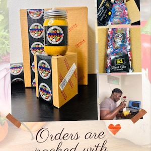 May include: A close-up of a jar of yellow sauce with a label that says "Zefis" and a red, white, and green logo. The jar is sitting on top of a brown box with the word "FRAGILE" printed on it. The box is surrounded by other brown boxes with the same label. The image also shows a person holding a similar jar of sauce and a laptop. The text "Orders are packed with love" is written on the bottom of the image.