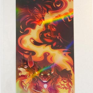 May include: A rectangular holographic art print featuring a dynamic illustration of five stylized cats with expressive faces. The artwork uses a vibrant color palette of deep reds, oranges, and yellows, with a rainbow light effect across the center.