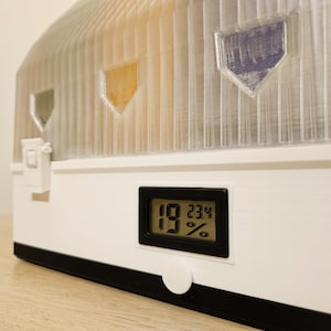 4‑spool modular 3D‑printed drybox with clear front windows and humidity and temperature display.