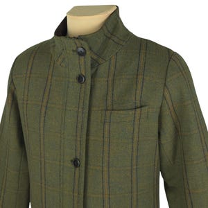 Puede incluir: Una chaqueta de cuadros verde, marrón y azul con cuello alto y cierre de botones.