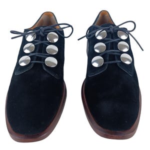 May include: Black suede lace-up shoes with silver metal accents on the laces.