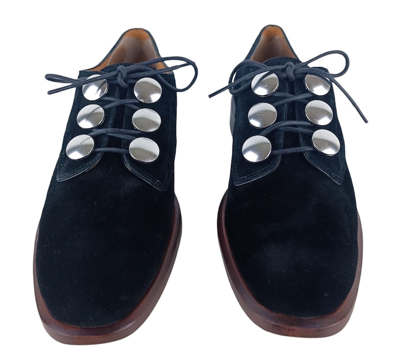 May include: Black suede lace-up shoes with silver metal accents on the laces.