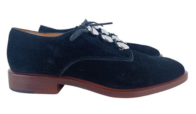 May include: Black suede lace-up shoes with silver metal accents on the laces.