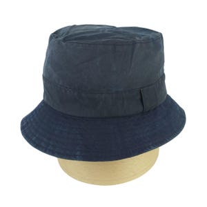 May include: A dark navy blue bucket hat featuring a flat crown and a downward-sloping brim. The hat is constructed from a solid-colored fabric with a visible horizontal band detail encircling the base of the crown, providing a structured appearance.