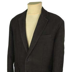 May include: A dark charcoal blazer with a notched lapel, two-button closure, and a chest pocket. The jacket is displayed on a mannequin with a cream-colored shirt underneath. The blazer has a classic, tailored design.