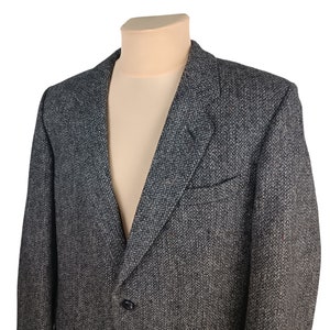 Op de afbeelding: Een grijs tweed blazer met een enkele knoopsluiting. De blazer heeft een klassieke pasvorm en een subtiel herringbone patroon.