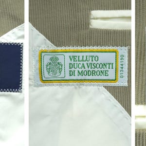 May include: Close-up of a beige fabric with three labels. The first label is navy blue with the brand "BOGGI MILANO". The second label is green and yellow with the text "VELLUTO DUCA VISCONTI DI MODRONE". The third label has fabric composition and size information.
