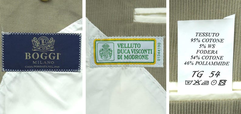 May include: Close-up of a beige fabric with three labels. The first label is navy blue with the brand "BOGGI MILANO". The second label is green and yellow with the text "VELLUTO DUCA VISCONTI DI MODRONE". The third label has fabric composition and size information.