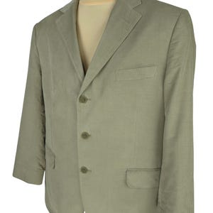 May include: A light green blazer with a three-button closure and notched lapels. The blazer has two front pockets and a chest pocket. The jacket is displayed on a mannequin.