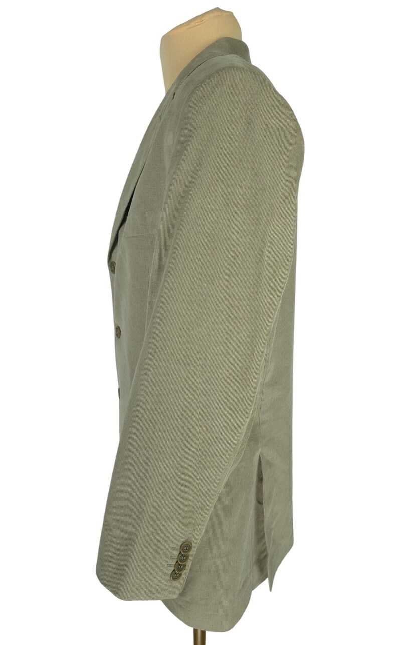 May include: A light green corduroy blazer displayed on a mannequin. The blazer has a notched lapel, three buttons on the sleeve cuffs, and two buttons on the front. The fabric has a vertical ribbed texture.