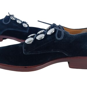 May include: Black suede lace-up shoes with silver metal button accents.