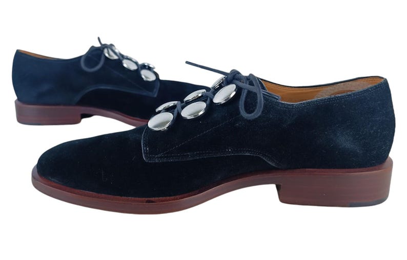 May include: Black suede lace-up shoes with silver metal button accents.