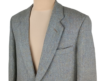 May include: A light blue herringbone blazer with a single-button closure and a notched lapel. The jacket has a chest pocket and is displayed on a mannequin. The fabric has flecks of blue, brown, and yellow.
