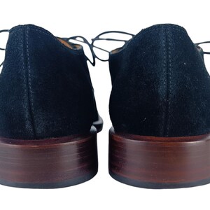 May include: A pair of black suede lace-up shoes with brown leather soles.