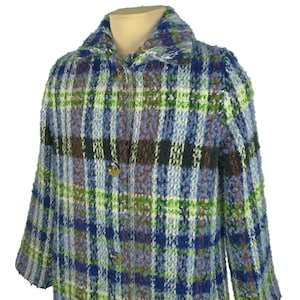 Op de afbeelding: Een vintage jas met een veelkleurig ruitpatroon. De jas heeft een klassieke kraag en knoopsluiting. Het ruitontwerp bevat tinten blauw, groen, bruin en wit. De jas is gemaakt van een textuurstof.