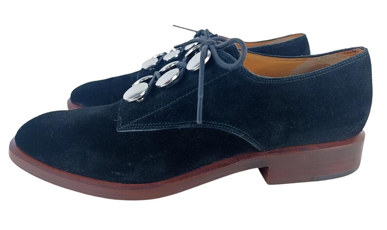 May include: Black suede lace-up shoes with silver metal accents on the laces.