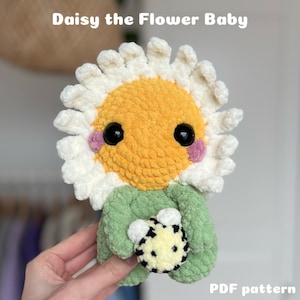 Könnte beinhalten: Häkelanleitung für ein Baby-Spielzeug in Form einer Gänseblümchen-Blume. Das Spielzeug ist gelb und weiß mit einem grünen Körper und einem schwarz-weißen Ball in den Händen. Die Anleitung ist als PDF-Download verfügbar.