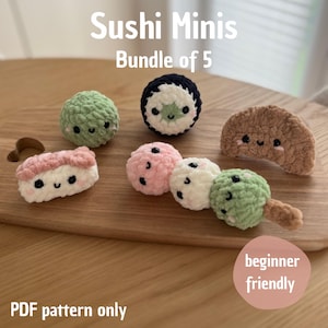 Może przedstawiać: Kolekcja pięciu szydełkowych miniatur sushi, w tym rolka, nigiri i dango, ułożonych na drewnianej powierzchni. Kawałki sushi są w różnych kolorach, takich jak zielony, różowy, biały i brązowy, z uśmiechniętymi twarzami. Tekst: "Sushi Minis Bundle of 5".