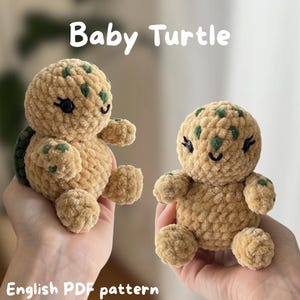Könnte beinhalten: Zwei handgefertigte Baby-Schildkröten aus Häkelarbeit in Hellbraun mit grünen Punkten auf dem Kopf und dunkelgrünen Panzer. Die Schildkröten haben schwarze Augen und lächelnde Gesichter. Der Text "Baby Turtle" steht über den Schildkröten und "English PDF pattern" darunter.