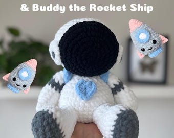May include: A crochet pattern for a white astronaut with a black helmet and a blue heart, and a small grey and pink rocket ship. The pattern is called "Nova the Astronaut & Buddy the Rocket Ship" and is available as a PDF download.