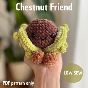May include: A crocheted chestnut character with a smiling face, nestled in a green and yellow crocheted shell. The text "Chestnut Friend" and "PDF pattern only" are visible. The design includes two small, brown crocheted feet.
