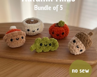 Puede incluir: Colección de cinco mini figuras de ganchillo con temática otoñal, que incluyen una calabaza, una bellota y otras formas de temporada. Las figuras son en tonos marrones, naranjas y verdes, con caras sonrientes.