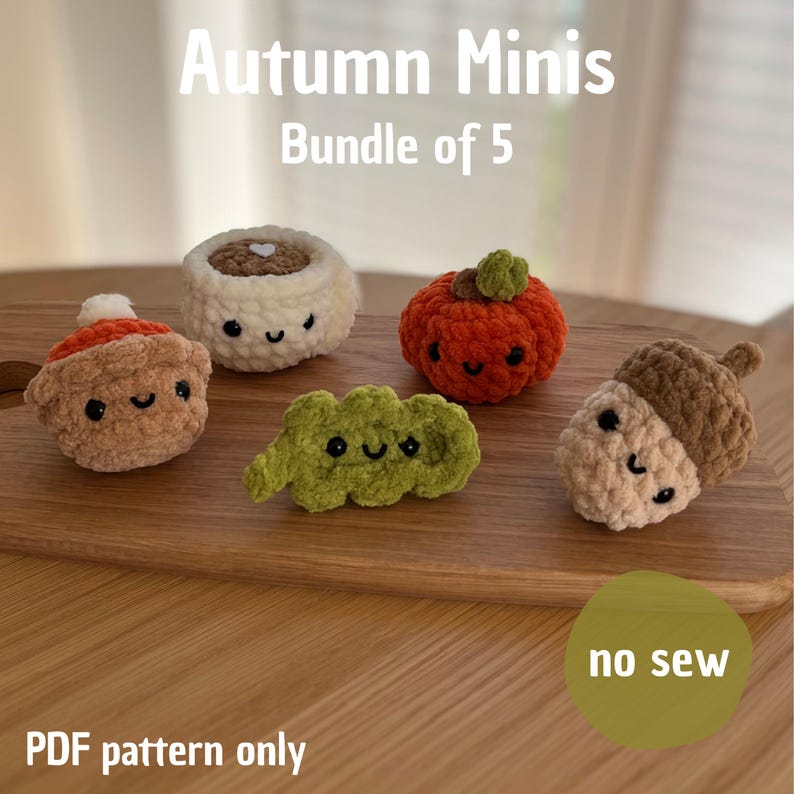 May include: A set of five crocheted autumn-themed mini figures, including a pumpkin, acorn, and other seasonal shapes. The figures are in shades of brown, orange, and green, with smiling faces. The text "Autumn Minis Bundle of 5" is at the top.