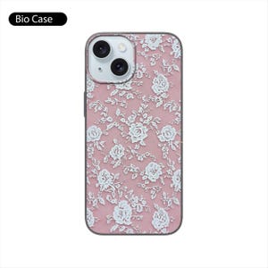 May include: A pink phone case with a white lace pattern. The case has a cutout for the camera lens.