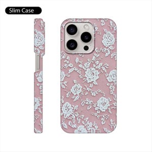 May include: A pink phone case with a white lace pattern. The case has a cutout for the camera lens and a raised lip around the edges to protect the screen.