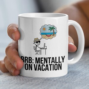 Könnte beinhalten: Weißer Keramikbecher mit dem Text "BRB: MENTALLY ON VACATION" in Schwarz. Der Becher zeigt eine Cartoon-Figur an einem Computer, die von einer Strandszene mit Palme, Sonne und Hängematte träumt. Ein lustiger, neuartiger Artikel.