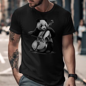 May include: A black t-shirt with a graphic of a panda bear playing a cello. The panda is black and white and the cello is gray.