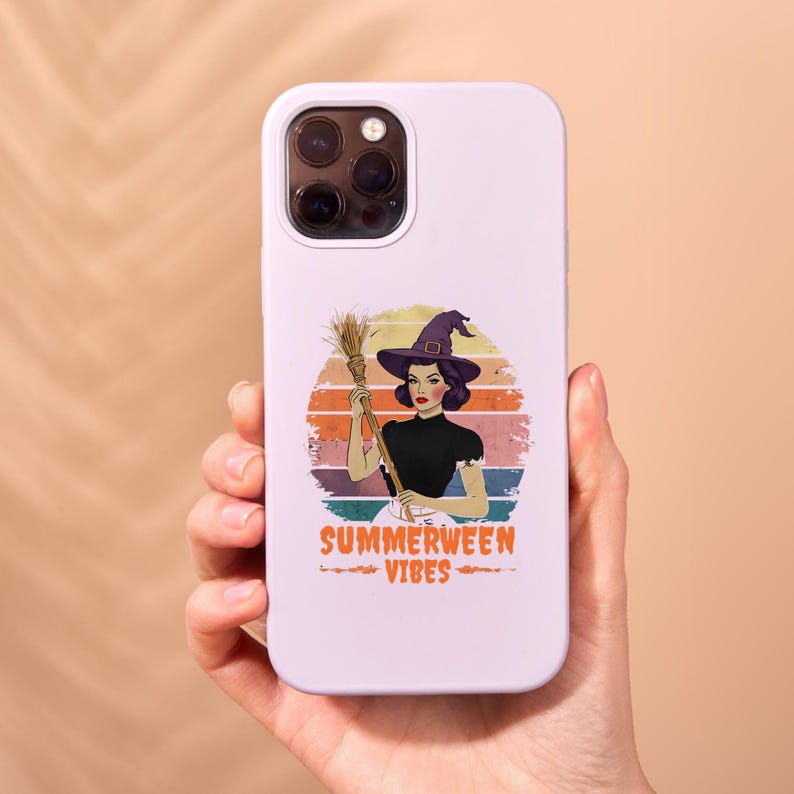 Puede incluir: Una funda de tel&eacute;fono blanca con una ilustraci&oacute;n retro de una mujer con un sombrero de bruja sosteniendo una escoba contra un fondo de puesta de sol. El texto "SUMMERWEEN VIBES" se muestra en naranja. La funda se sostiene en una mano.