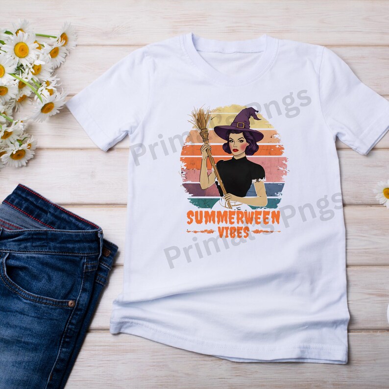 Puede incluir: Camiseta blanca con una ilustraci&oacute;n retro de una mujer con sombrero de bruja sosteniendo una escoba. El dise&ntilde;o incluye el texto "Summerween Vibes" en naranja, sobre un fondo con colores de atardecer. La camiseta se combina con unos vaqueros azules.