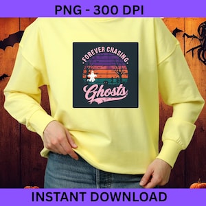 Op de afbeelding: Een lichtgeel sweatshirt met een Halloween-ontwerp. De afbeelding toont een zonsondergang met bomen, een spook en de woorden "Forever Chasing Ghosts". De tekst "Instant Download" staat onderaan.
