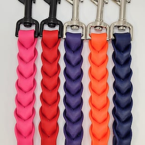 May include: Five colorful dog leash attachments with braided leather straps. The colors are pink, red, purple, orange, and navy blue. Each leash has a metal clasp and a snap closure.