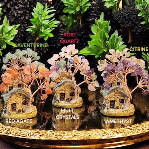May include: Five miniature stone houses with trees made of wire and various colored gemstones. The houses are on a gold tray. The trees are labeled with the types of gemstones used: Red Agate, Multi Crystals, Amethyst, Rose Quartz, and Citrine.