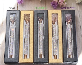 May include: Five black boxes with gold trim, each containing a crystal-topped pen. The boxes are labelled with the names of different crystals: Opal, Fluorite, Amethyst, Citrine, and Rose Quartz.
